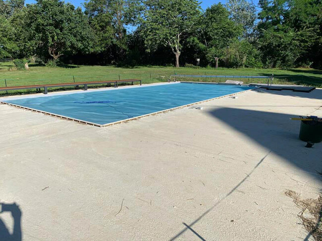 Piscine domestique avec volet de protection bleu dans un grand environnement