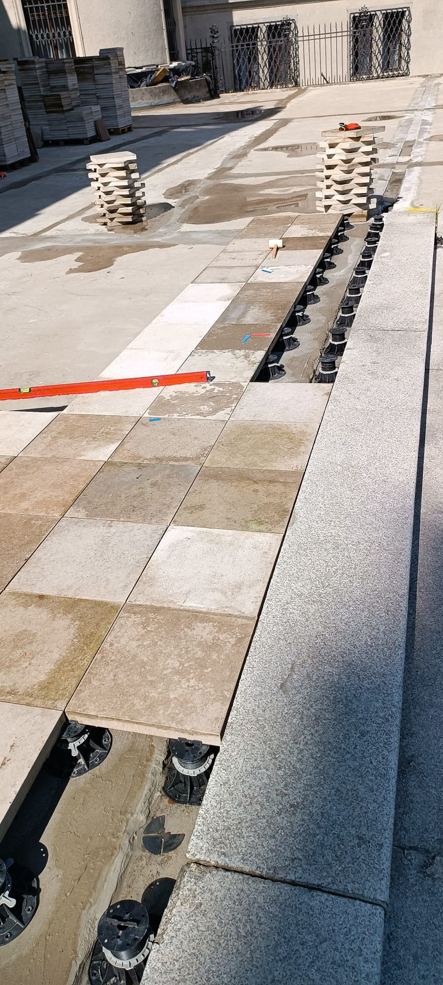Pose de dalles de terrasse beiges sur plots noirs