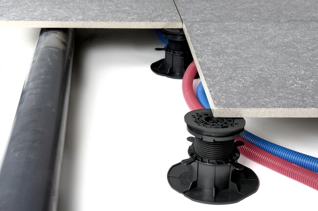 Installation de plomberie et d'électricité réalisée sous une terrasse surélevée avec plots