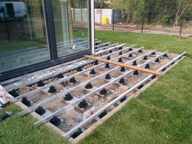 Construction d'une terrasse surélevée sur le sol dans le jardin avec des plots et des lames en composite