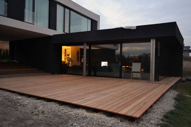 Moderne terrasse en planches de bois et fenêtres coulissantes.