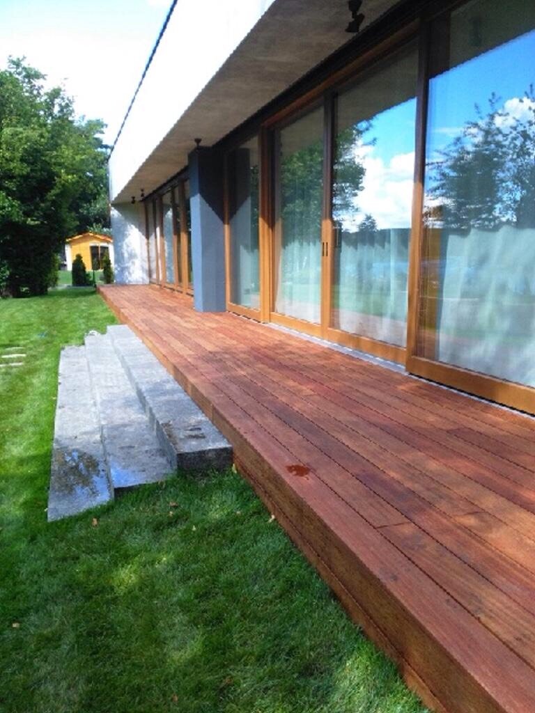 Aménagement d'une terrasse avec des dalles en grès, des fauteuils en rotin et des plantes.