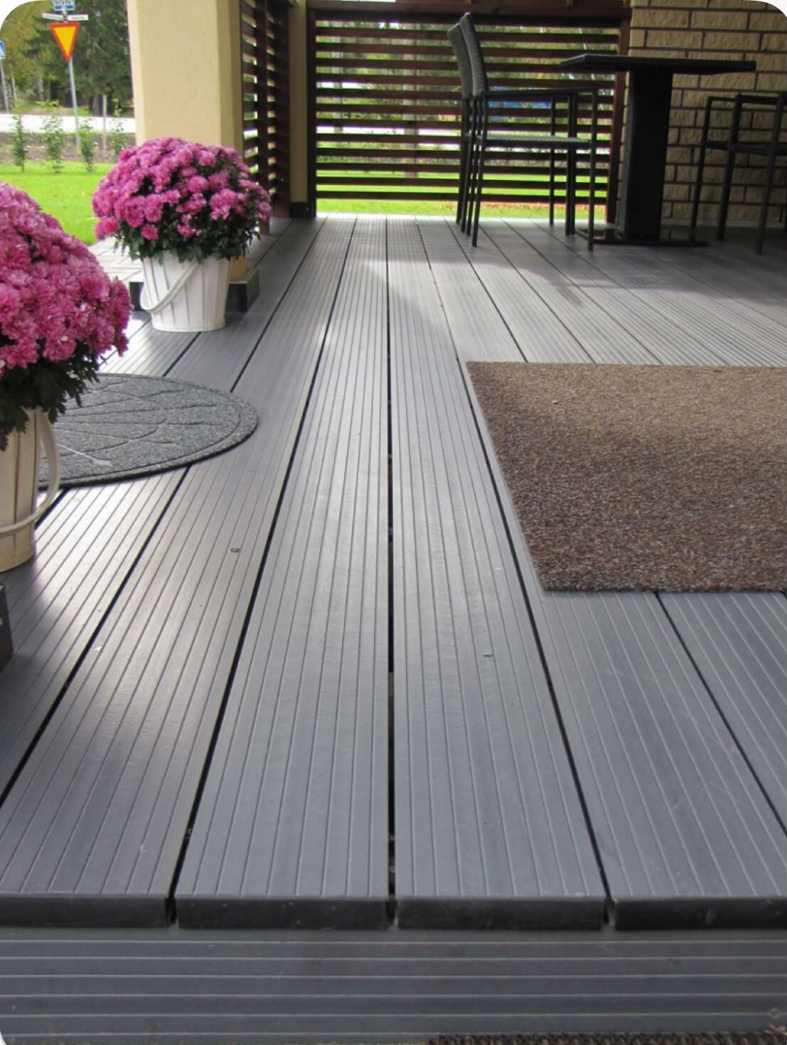 Terrasse en bois avec olivier et banc de jardin.