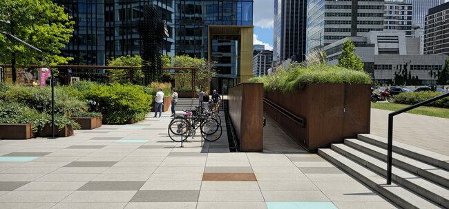 Dalles de terrasse grand format sur une place publique devant un immeuble de bureaux moderne.