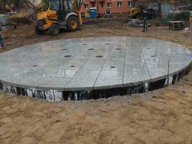 Construction d'une fontaine urbaine circulaire en dalles de granit gris sur la place