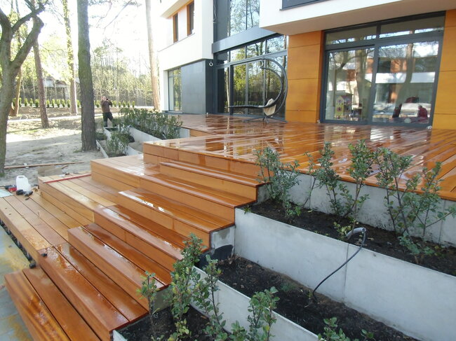 Terrasse surélevée en cascade avec des lames en bois exotique et escaliers de jardin en bois.