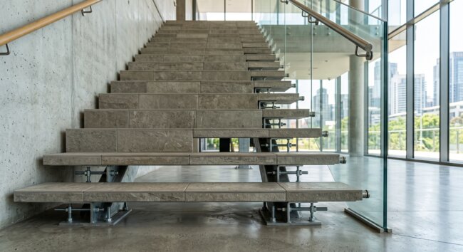 Escaliers en pierre modernes et garde-corps en verre dans un intérieur industriel