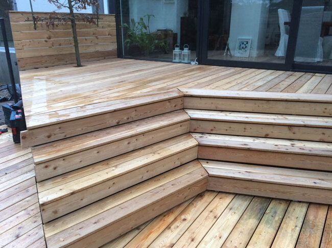 Moderne terrasse en bois avec escaliers d'angle et portes coulissantes en verre