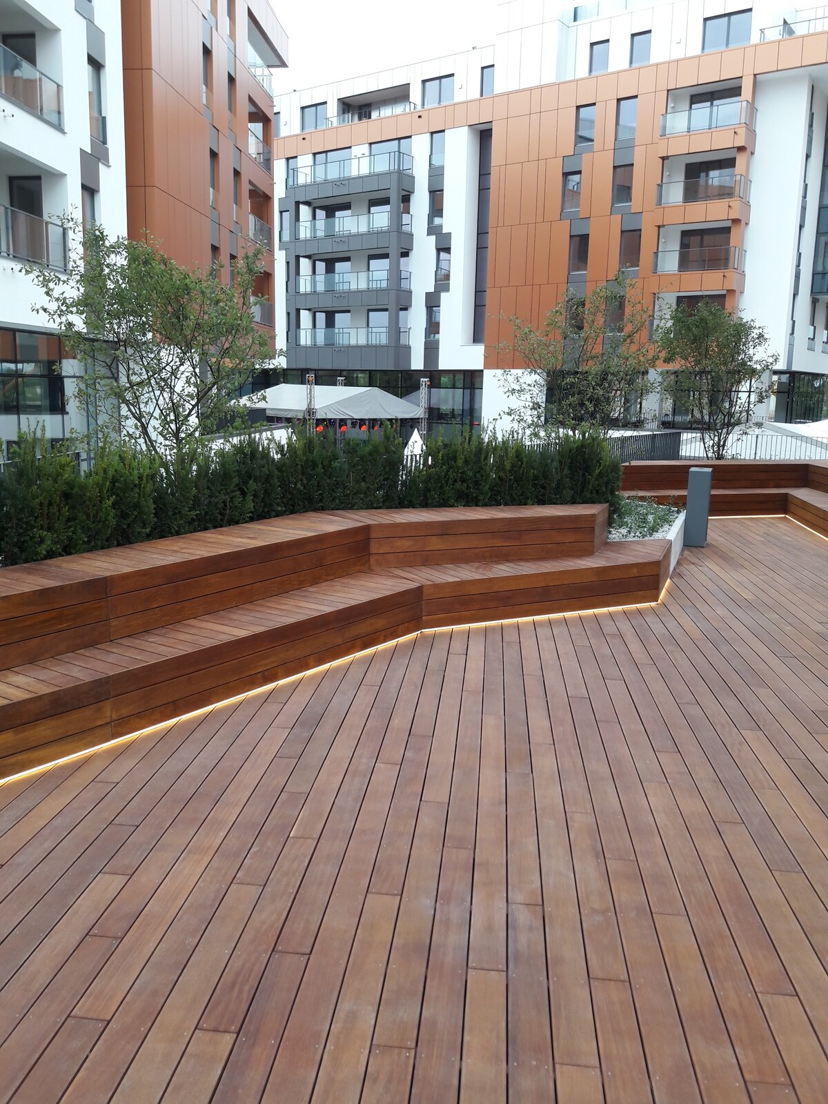 Moderne terrasse avec bancs en bois et éclairage LED sur fond d'immeubles résidentiels