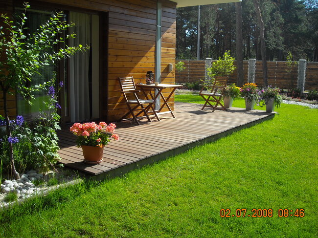 Terrasse en bois dans le jardin avec du mobilier de terrasse et des fleurs
