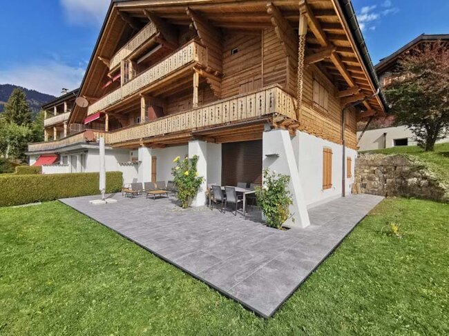 Terrasse Surélevée avec dalles en grès cérame foncées près d'une maison en bois de style alpin