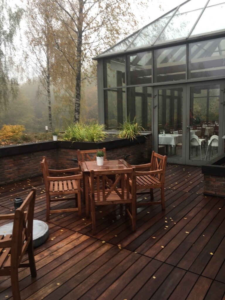 Terrasse en bois de jardin avec mobilier et jardin d'hiver en arrière-plan