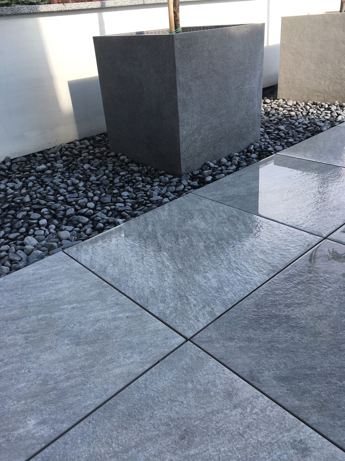 Dalles en grès gris sur une terrasse avec une bordure en pierre et un pot de fleurs