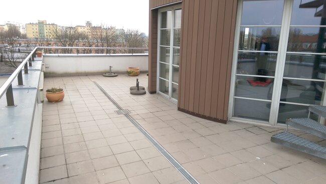 Grande terrasse avec dalles et drain linéaire sur le toit du bâtiment