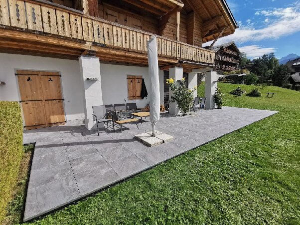 Terrasse sur membrane bitumineuse thermosoudable, terrasse extérieure avec dalles en grès cérame grises près d'un bois vers