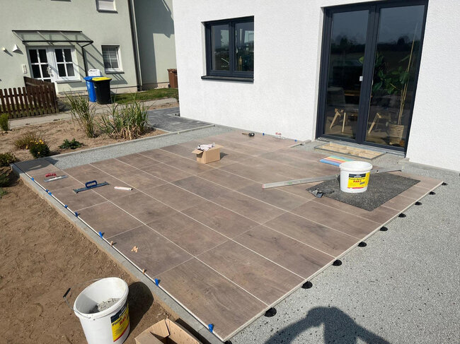 Construction d'une terrasse surélevée avec des dalles en grès cérame imitant le bois à côté de la maison