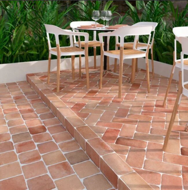 Terrasse en terre cuite avec mobilier de jardin et verdure en arrière-plan