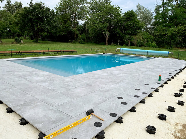 Terrasse en dalles avec piscine posée sur le sol sur une chape en béton sur plots spiral solver