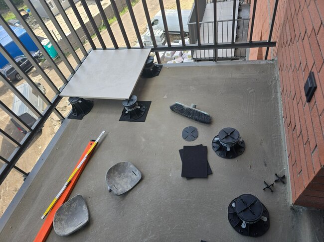 Première dalle posée sur le balcon après mise à niveau sur plot réglable standard