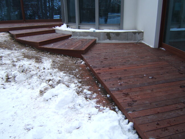 Escalier en bois et terrasse exotique en hiver recouverts de neige.