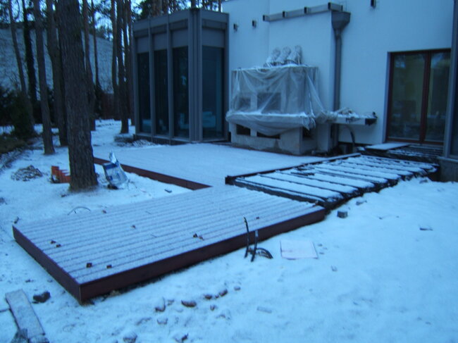 Construction d'une terrasse en bois devant une maison moderne en hiver.