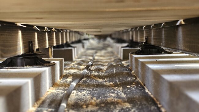 Vue de la sous-structure d'une terrasse en bois sur lambourdes et plots.