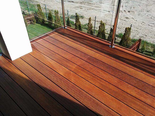 Balcon fini avec des lames en bois exotique avec garde-corps en verre.