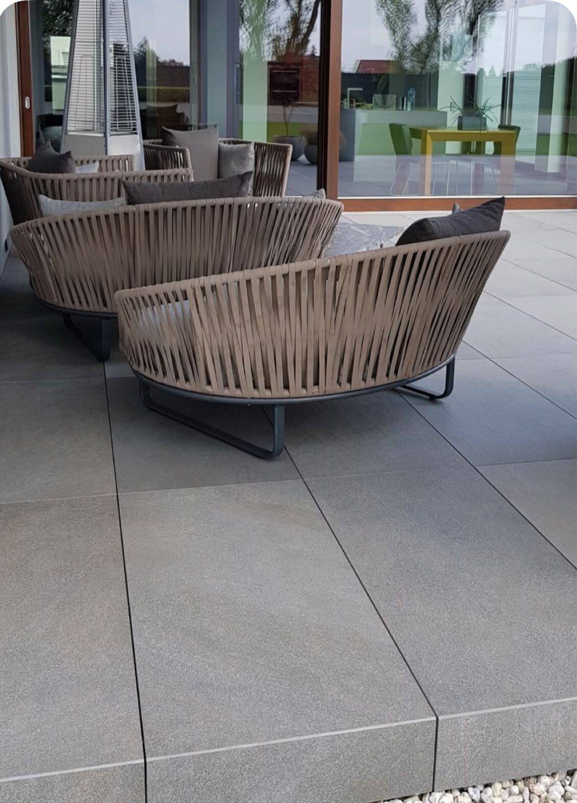 Terrasse moderniste en dalles de grès équipée de meubles de jardin en osier