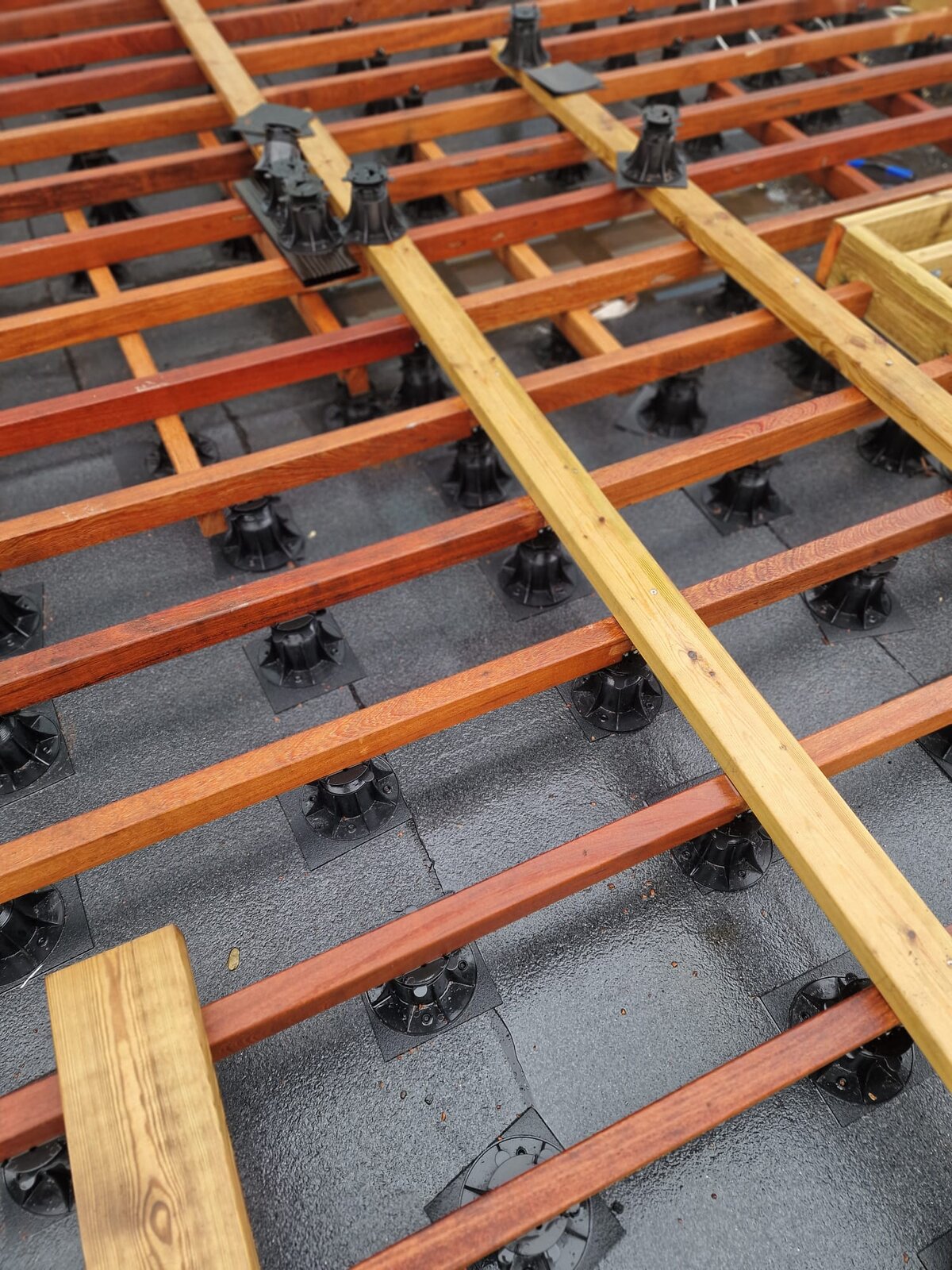 Montage de la sous-structure d'une terrasse en bois sur plots réglables.