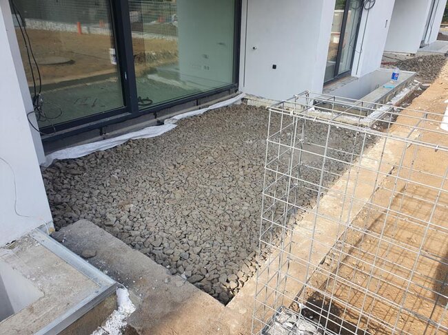 Sous-couche en pierre concassée pour terrasse de jardin.