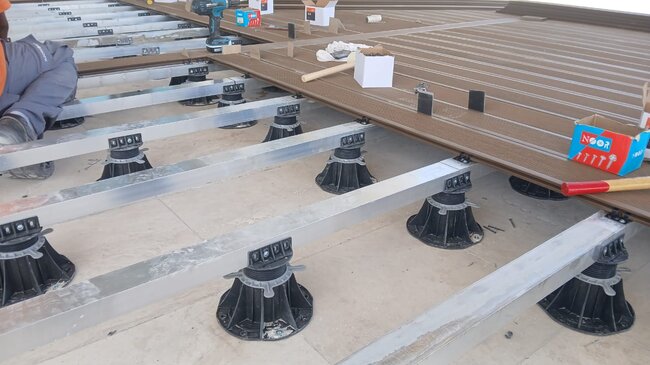 Construction d'une terrasse en lames composites sur plots réglables.
