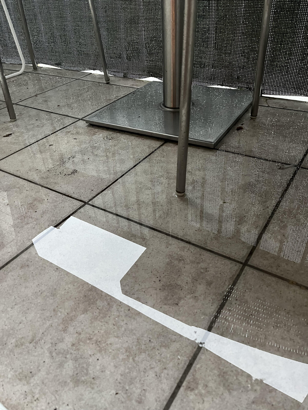 Kałuża i stojąca woda na płytkach balkonowych pod meblami