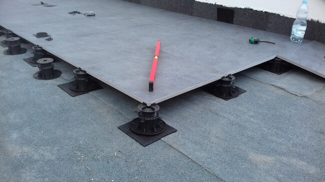 Plots réglables posés sur membrane bitumineuse thermosoudable avec patins en granulés en caoutchouc SBR