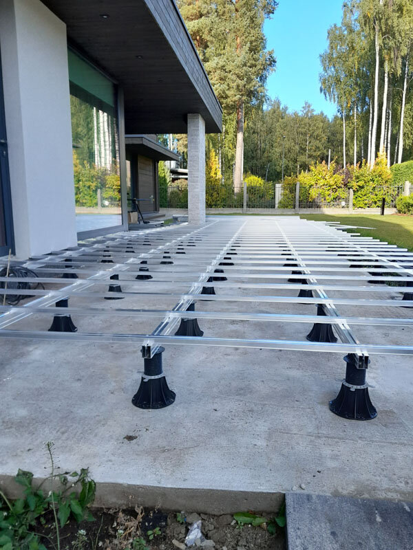 Plots standard avec adaptateurs pour lambourdes, posés avec lambourdes en aluminium sur une terrasse sur sol.