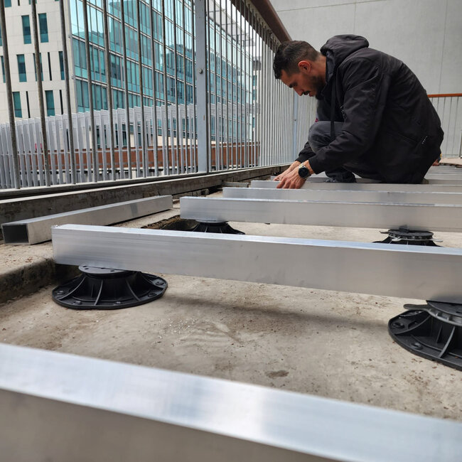 Installation de lambourdes aluminium soutenues par des plots de terrasse réglables en plastique