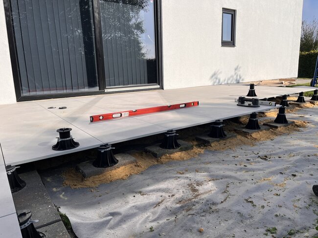Installation de dalles de terrasse extérieures surélevées à l'aide de plots de terrasse réglables.
