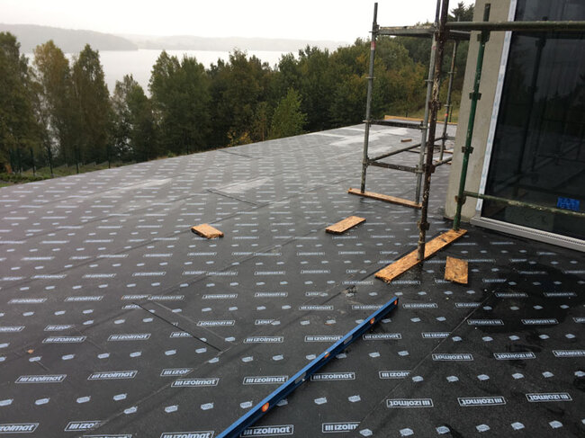 Toit plat en construction avec pose d'une membrane d'étanchéité bitumineuse.