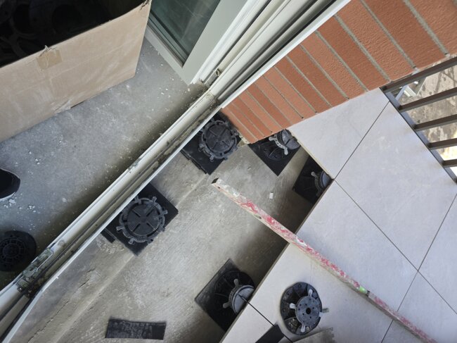 Installation d'un système de plancher surélevé sur plots pour la pose de dalles sur un balcon le long du bord.