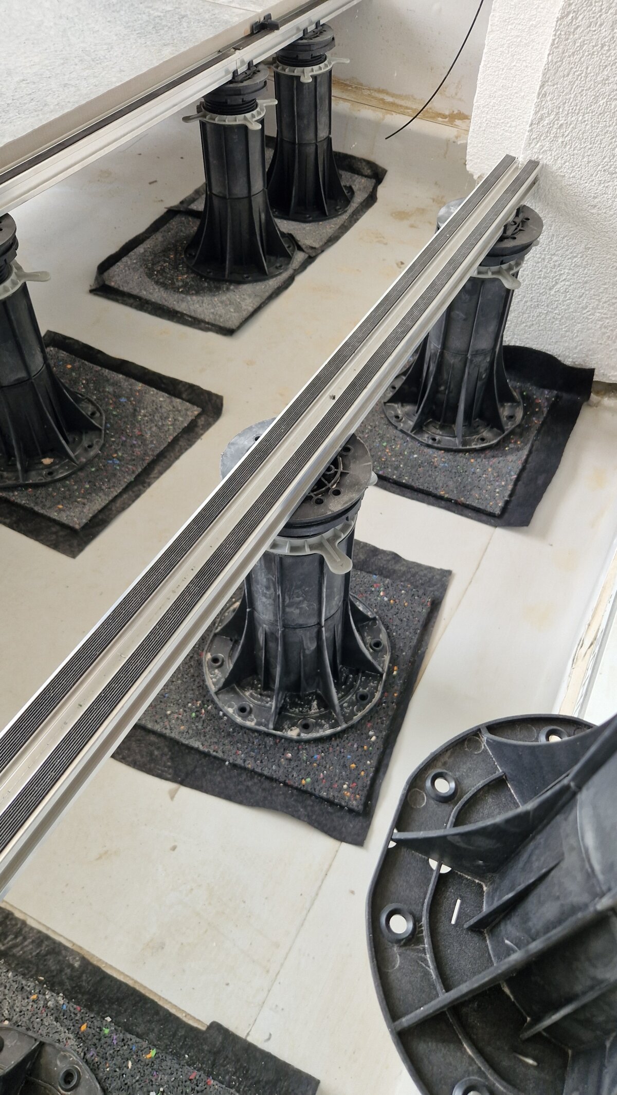Système de plots réglables avec lambourdes en aluminium pour l'installation d'une terrasse surélevée extérieure.