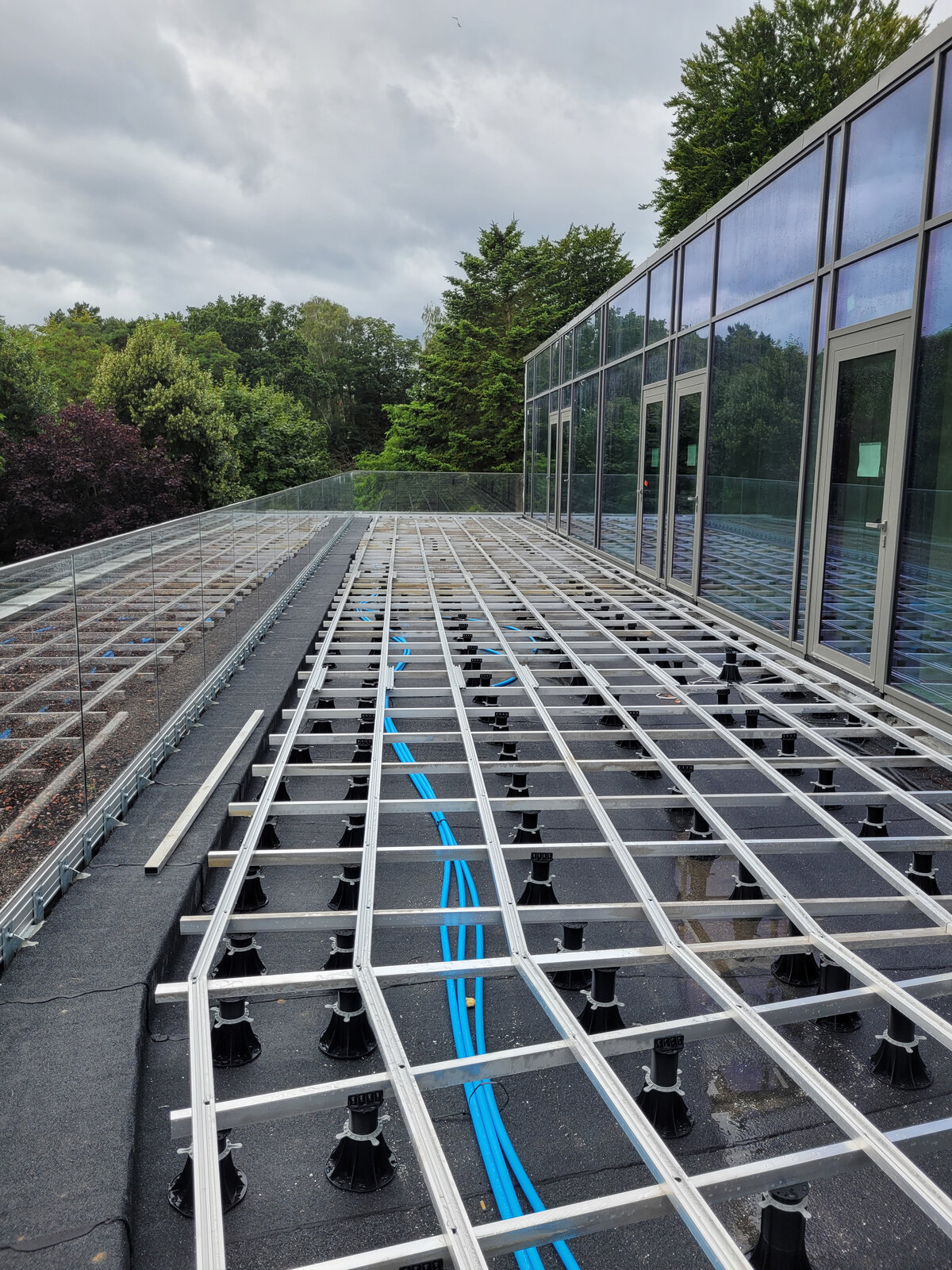 Structure de lambourdes en aluminium montée sur des plots réglables en plastique pour terrasses extérieures.