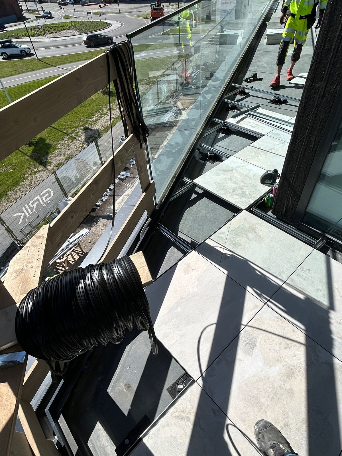 Système de plancher surélevé de balcon en cours de construction avec des dalles en porcelaine extérieures et des plots réglables.
