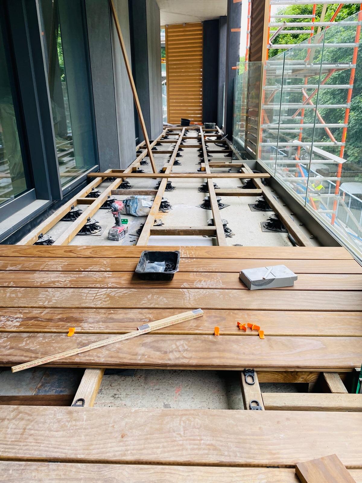 Installation d'une terrasse de balcon avec des lames de terrasse en bois dur posées sur une sous-structure réglable à plots.