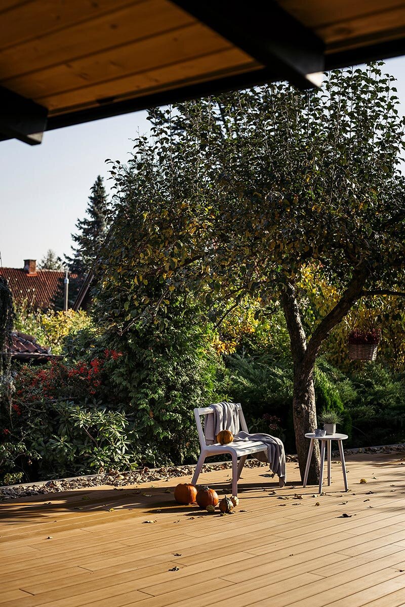 Terrasse de jardin confortable avec des dalles de terrasse composites modernes, décorée de citrouilles d'automne et de meubles de jardin.