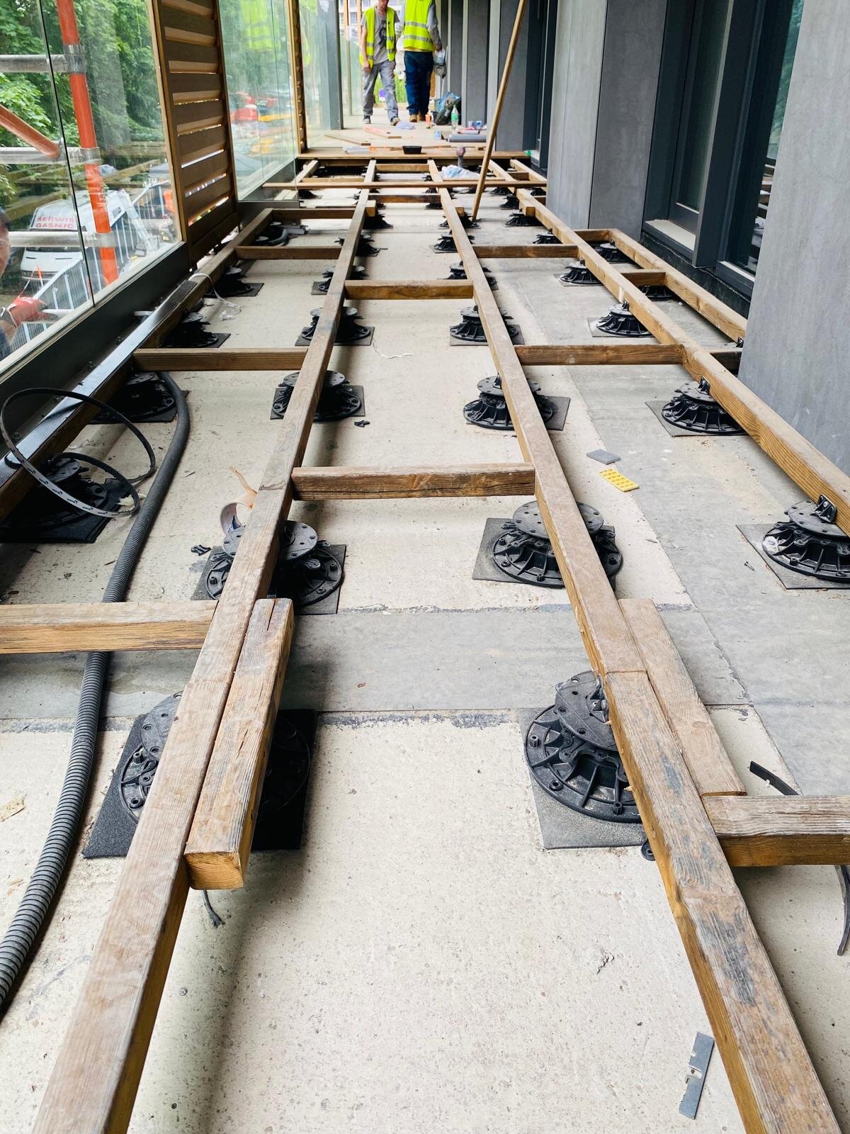 Plots réglables de terrasse et structure en lambourdes en bois montés sur une terrasse de balcon.
