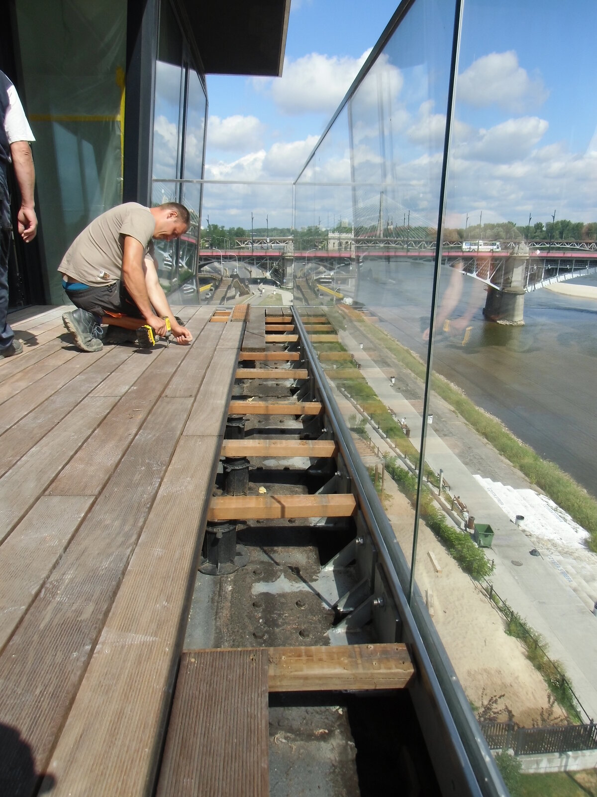Installateur posant une dalle de terrasse sur des plots réglables sur un balcon.