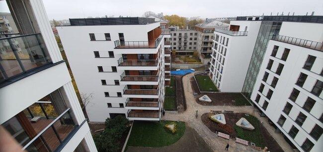 Vue aérienne en plongée d'un complexe résidentiel moderne avec balcons et cours aménagées.