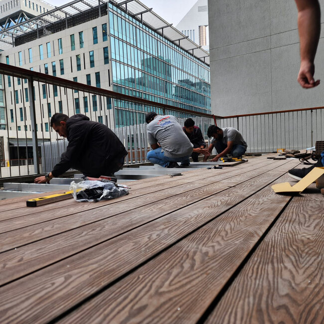 Installation d'une terrasse sur toit avec des lames en bois sur plots réglables et lambourdes.