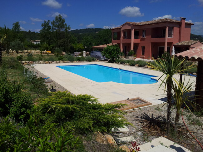 Terrasse de piscine en dalles extérieures soutenue par des plots réglables renforcés.