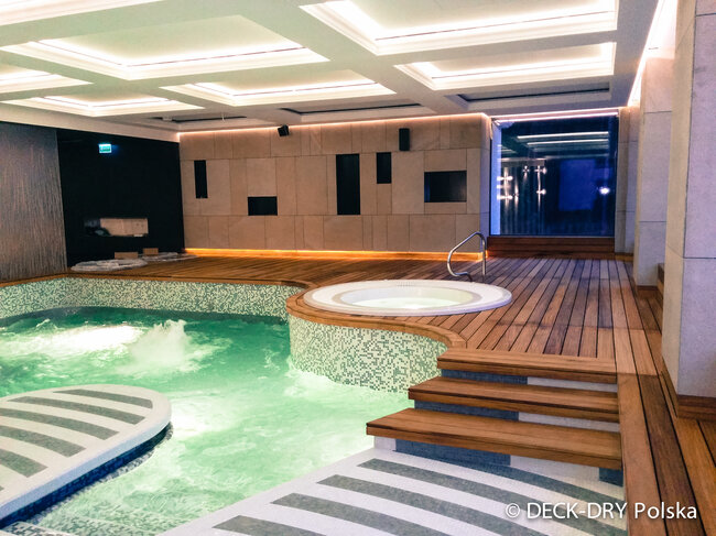 Terrasse en bois surélevée installée au-dessus d'une piscine intérieure à l'aide de plots réglables.