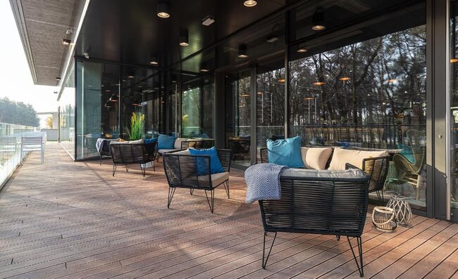 Mobilier de salon extérieur moderne disposé sur une terrasse en bois surélevée et propre.